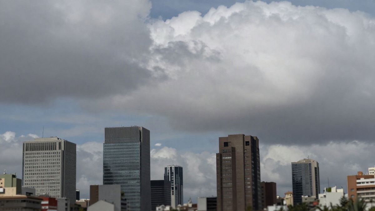 Illustrative image: wide view of a financial district with abstract elements representing cryptocurrencies and a dramatic sky.