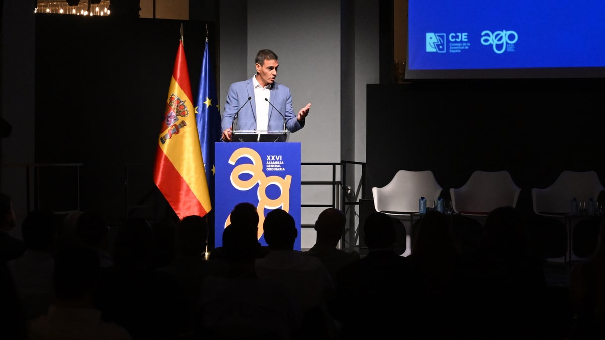 Imagen ilustrativa: un salón de actos vacío con sillas en semicírculo y un atril con micrófono al frente.