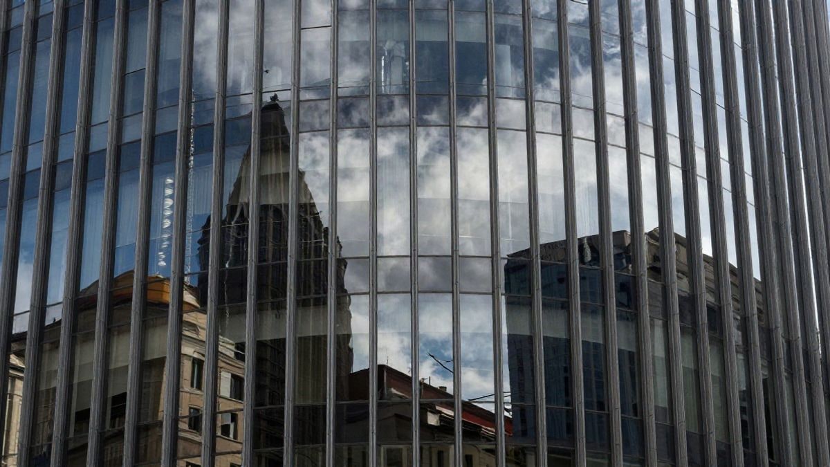 Imagen ilustrativa: edificio moderno de un banco con fachada de cristal y reflejos de la ciudad