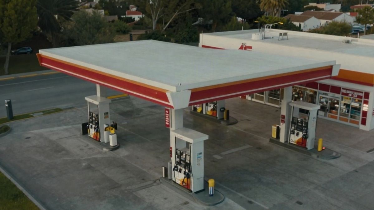 Illustrative image: aerial view of a modern petrol station with fuel pumps and shop, surrounded by greenery.