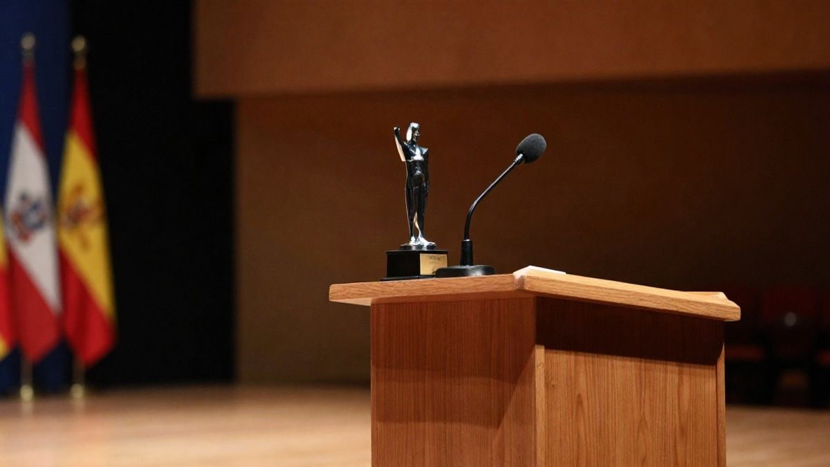 Illustrative image: a wooden lectern with a microphone and a small trophy on an empty stage