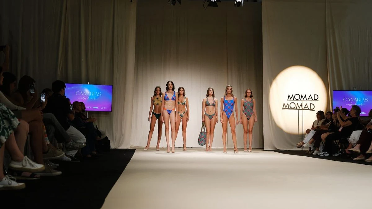 Imagen ilustrativa: pasarela de moda vacía con focos de luz y asientos a los lados, en un ambiente de feria comercial.
