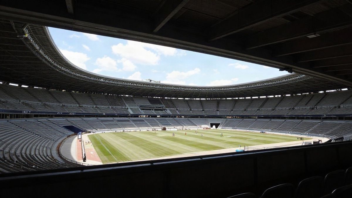 Illustrative image: interior view of a large stadium under construction, with natural light and an empty atmosphere, reflecting the magnitude of the sports project.
