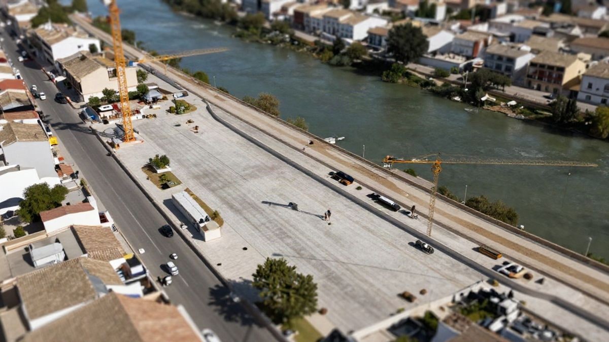 Imagen ilustrativa: vista cenital de un municipio español con obras de infraestructura hidráulica y zonas verdes de laminación natural.