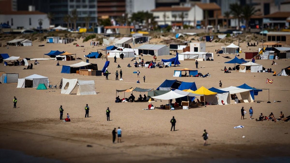 Illustrative image: aerial view of a beach with tents and makeshift shelters, with visible police presence in the area.