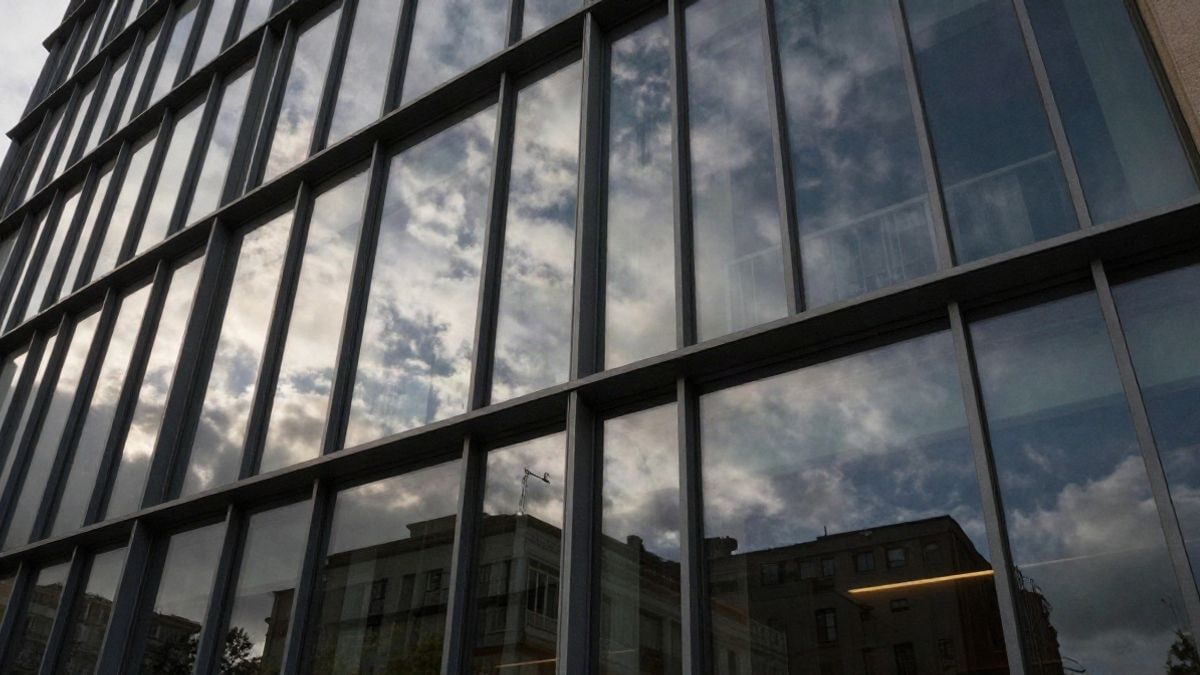 Imagen ilustrativa: fachada de un edificio de oficinas moderno con ventanales de cristal reflejando el cielo