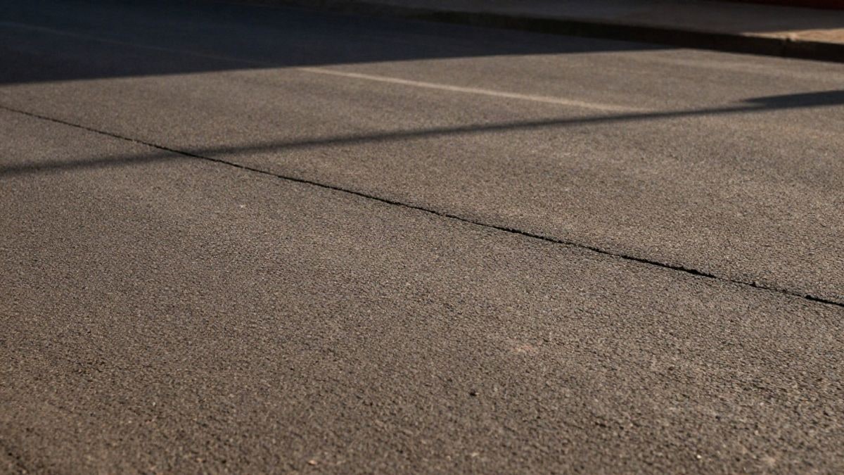 Illustrative image: detail of asphalt texture with recent repair marks