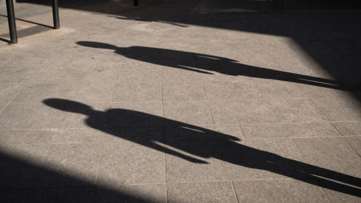 Imagen ilustrativa: Siluetas en un salón de juegos con luz dramática al atardecer, representando el sector del juego en España.