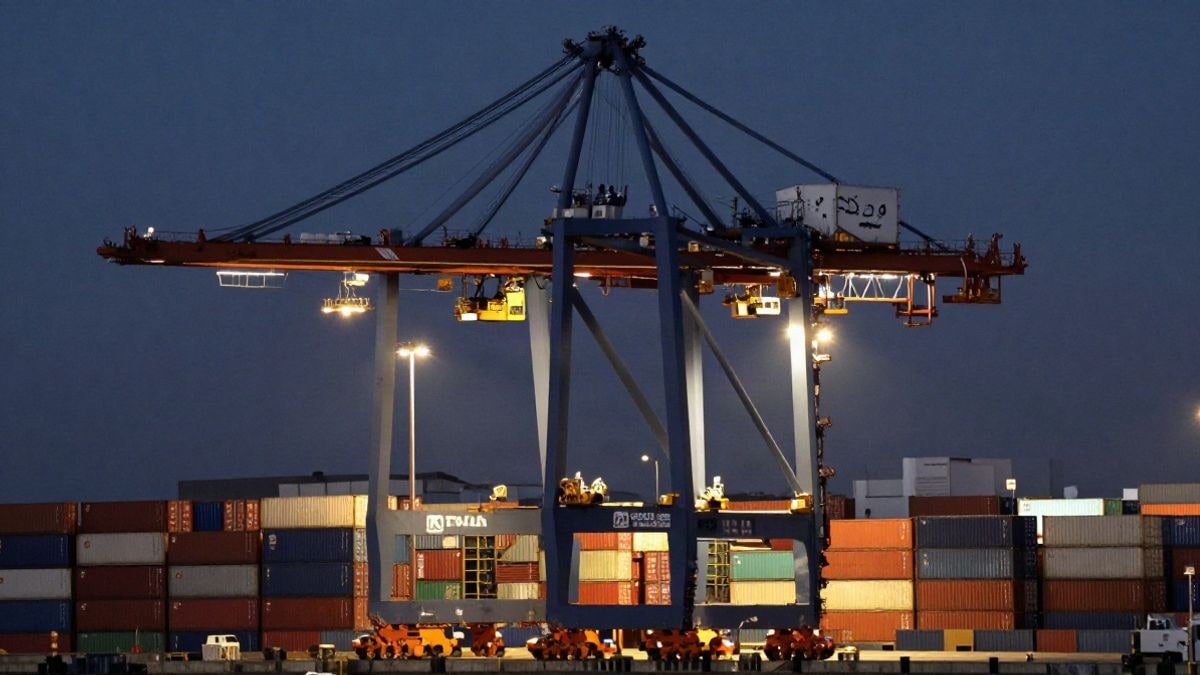 Illustrative image: modern port cranes illuminated at night, with stacked cargo containers in the background.