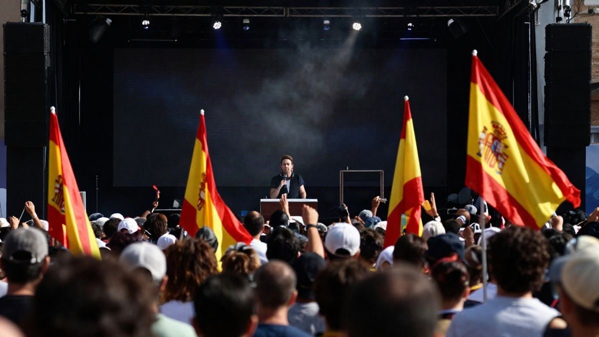 Imagen ilustrativa: una multitud en un mitin político con un escenario y banderas, enfatizando la atmósfera de compromiso político.